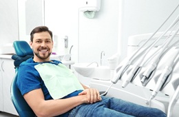 Man in blue shirt in dental chair looking at camera 